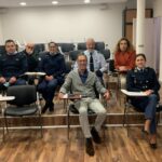 Sala de formação com cadeiras alinhadas na horizontal. (pessoas sentadas de frente para a câmara)