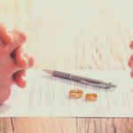 Sobre um contrato uma caneta e 2 alianças, 2 pares de mãos em cada extermidade do documento