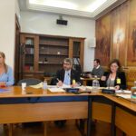 Sandra Ribeiro e Manuel Albano sentados a mesa com microfones e papeis.