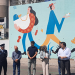 Várias individualidades frente a mural com mulher segurando galinha pesada e homem segurando pinto pequeno e leve