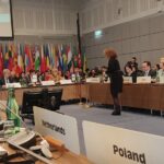 Sala do Plenário da conferência onde se vêem bandeiras e e placas em frentes aos representantes dos vários países