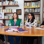 $ mulheres à volta duma mesa com os manuais expostos