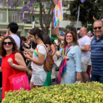várias pessoas desfilam com cartazes e bandeiras coloridas em apoio às pessoas lgbti+