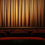 filas de cadeiras de veludo e palco com cortina fechada