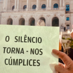 mão segura papel onde está escrito o silêncio torna-nos cúmplices