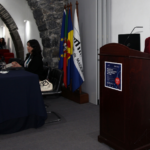 Sandra Ribeiro fal anum púlpito. na plateia, várias pessoas assistem.