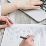mulher escreve num teclado de computador. outra mulher escreve num formulário de papel.